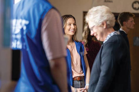 Volunteers in blue Hope vests smiling and greeting church members