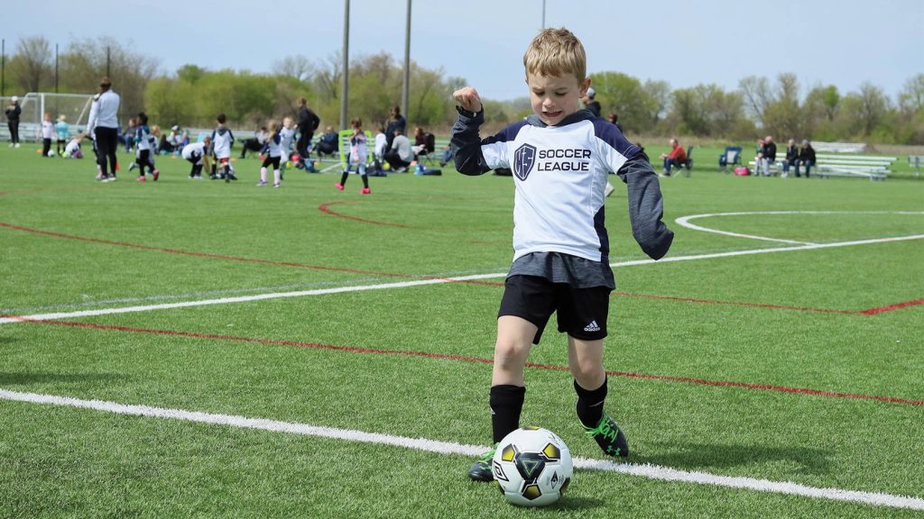 Boy wearing Hope Sports Soccer League jersey, kicking soccer ball