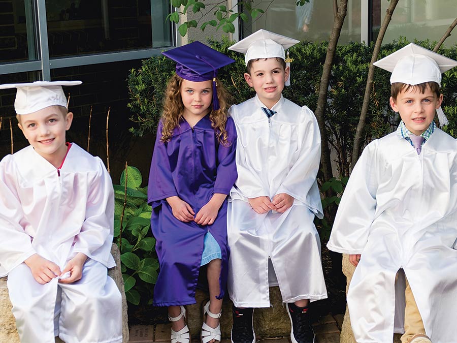 Four kids in graduation robes in the Prayer Garden