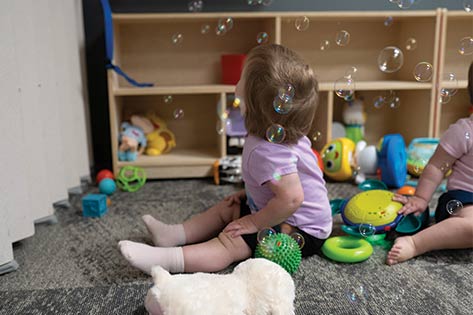 Daycare child looking at bubbles surrounded by toys