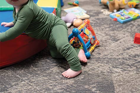Baby crawling on a building block with toys all around