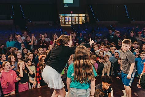 PowerLife middle school students playing game on stage and engaged in the audience