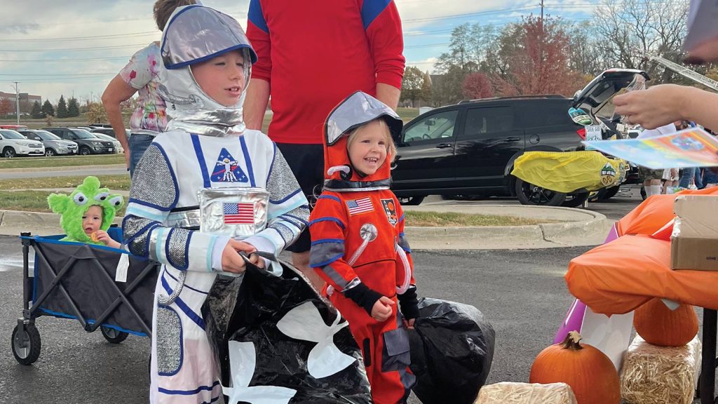 Kids smiling dressed in astronaut gear.