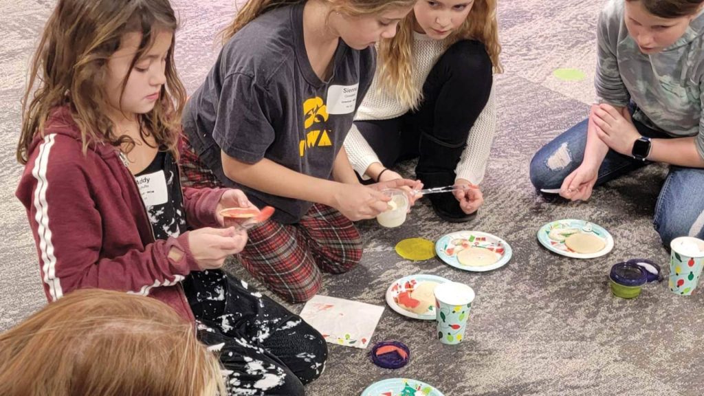 Girls decorating cookies in a circle.