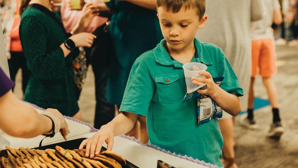 Boy in snack line grabbing a cookie.