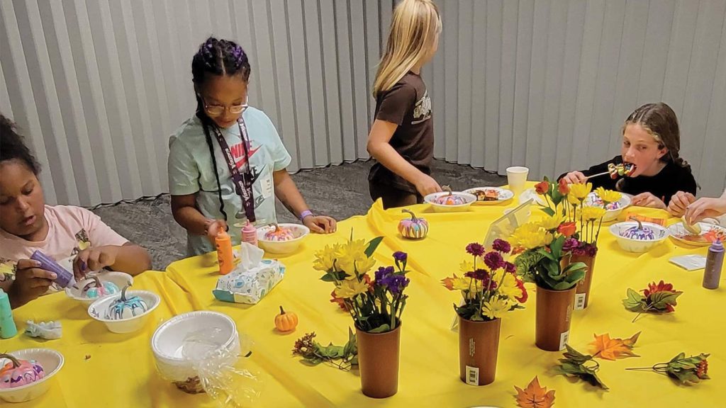 Girls doing floral craft around a table.