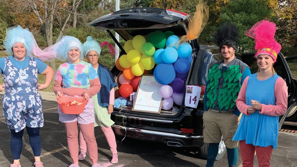 Group dressed in Trolls outfits and balloon-filled trunk.