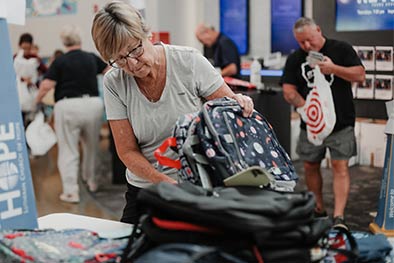 Volunteer woman sorting through donated backpacks for Back-to-School Drive