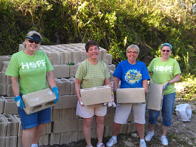 Four women carrying cinder blocks at global outreach build