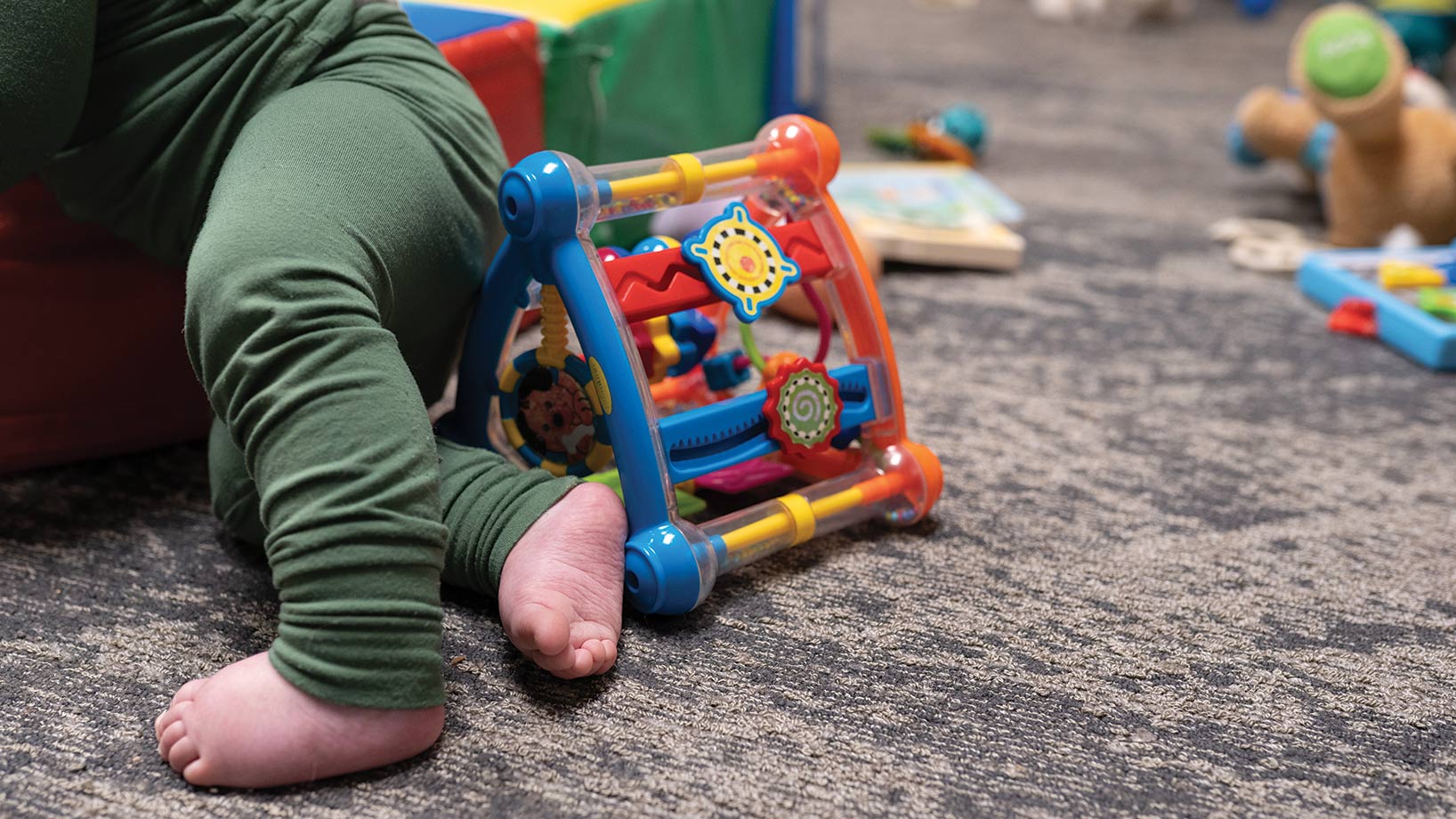 Baby feet next to a colorful toy