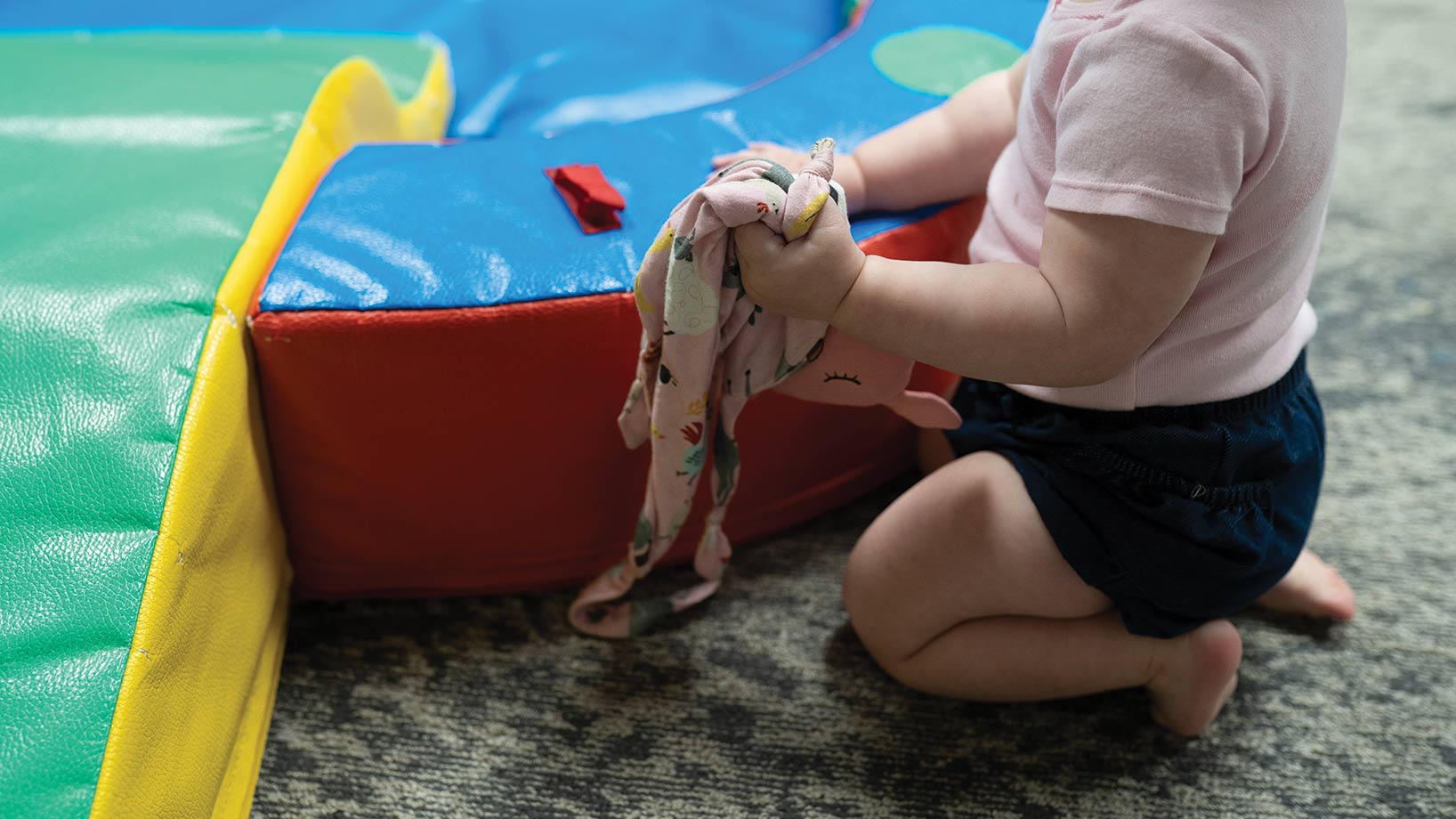 Child playing near colorful mats