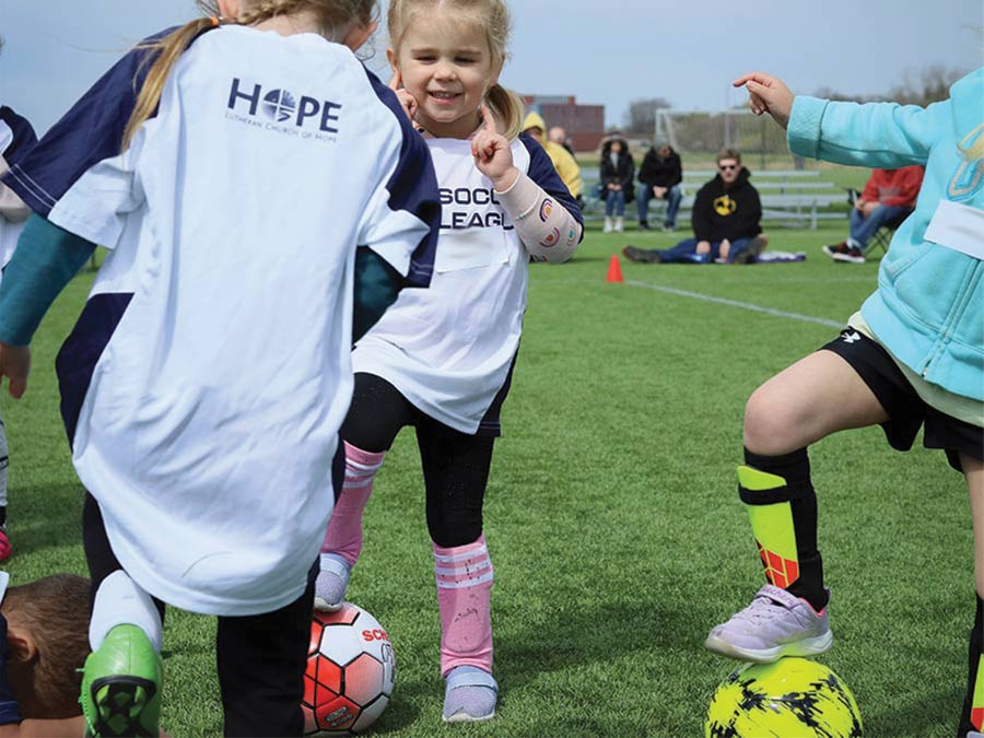 Little girls wearing Hope Sports soccer jerseys and kicking soccer balls