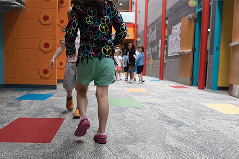 Kids in a line walking down colorful hallway