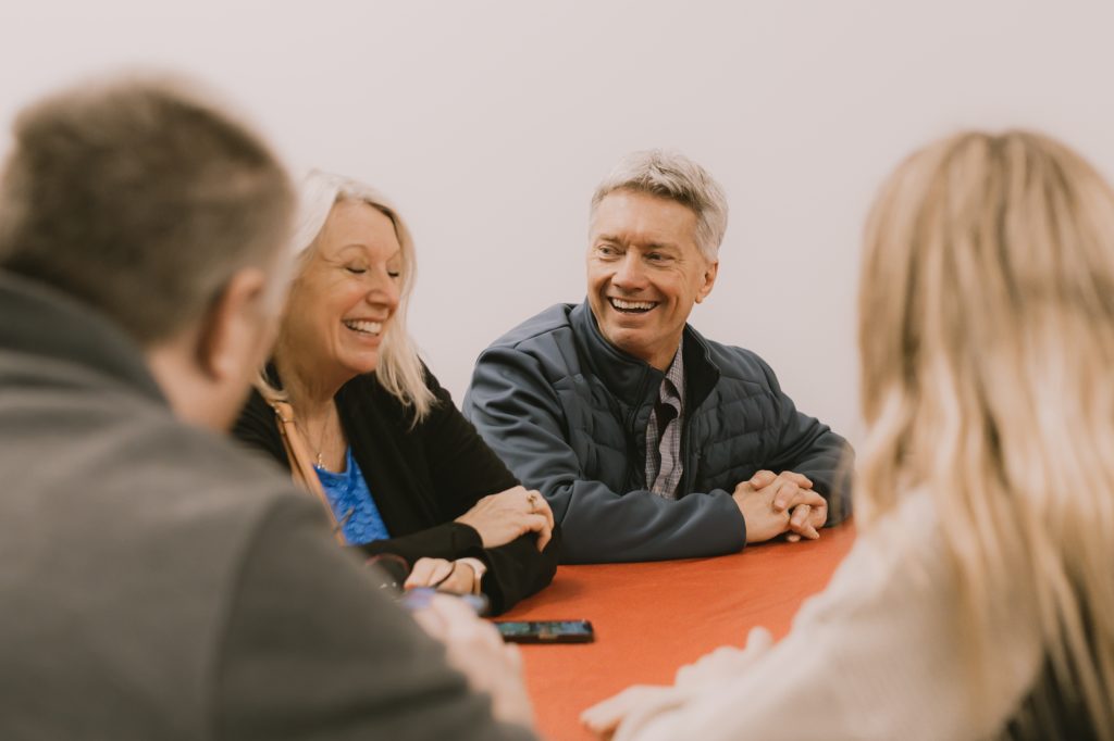 Group of four adults meeting , laughing, and talking with one another.