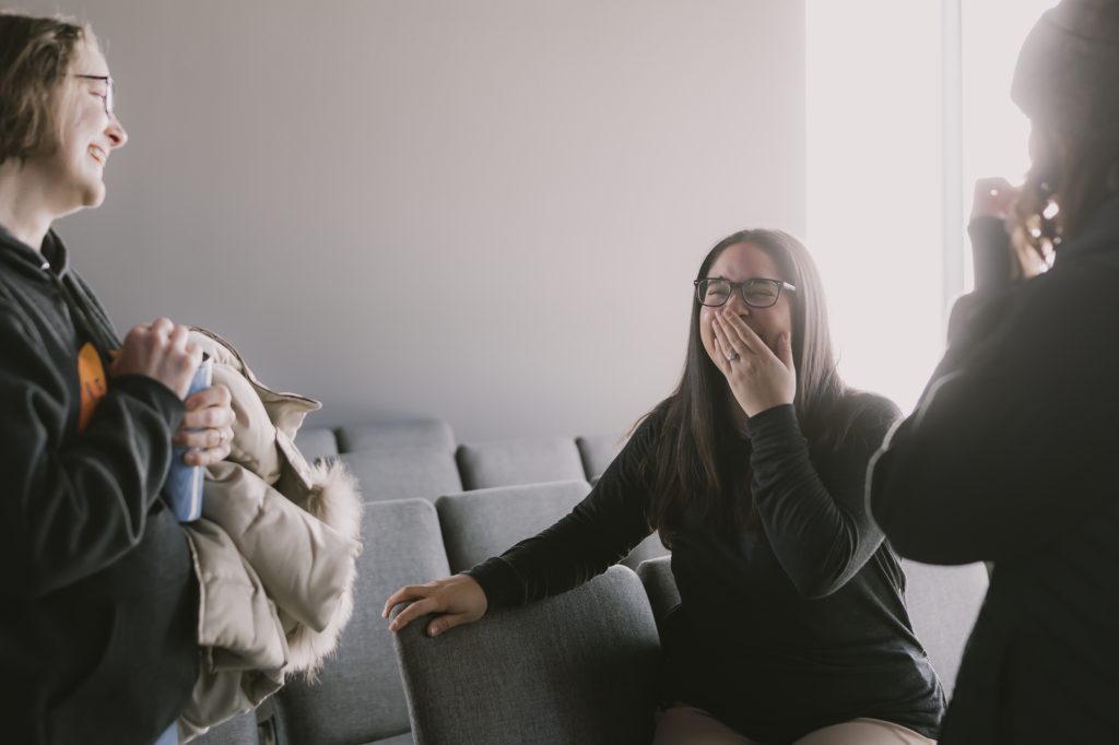 Group of three adults sitting in worship center chairs laughing.