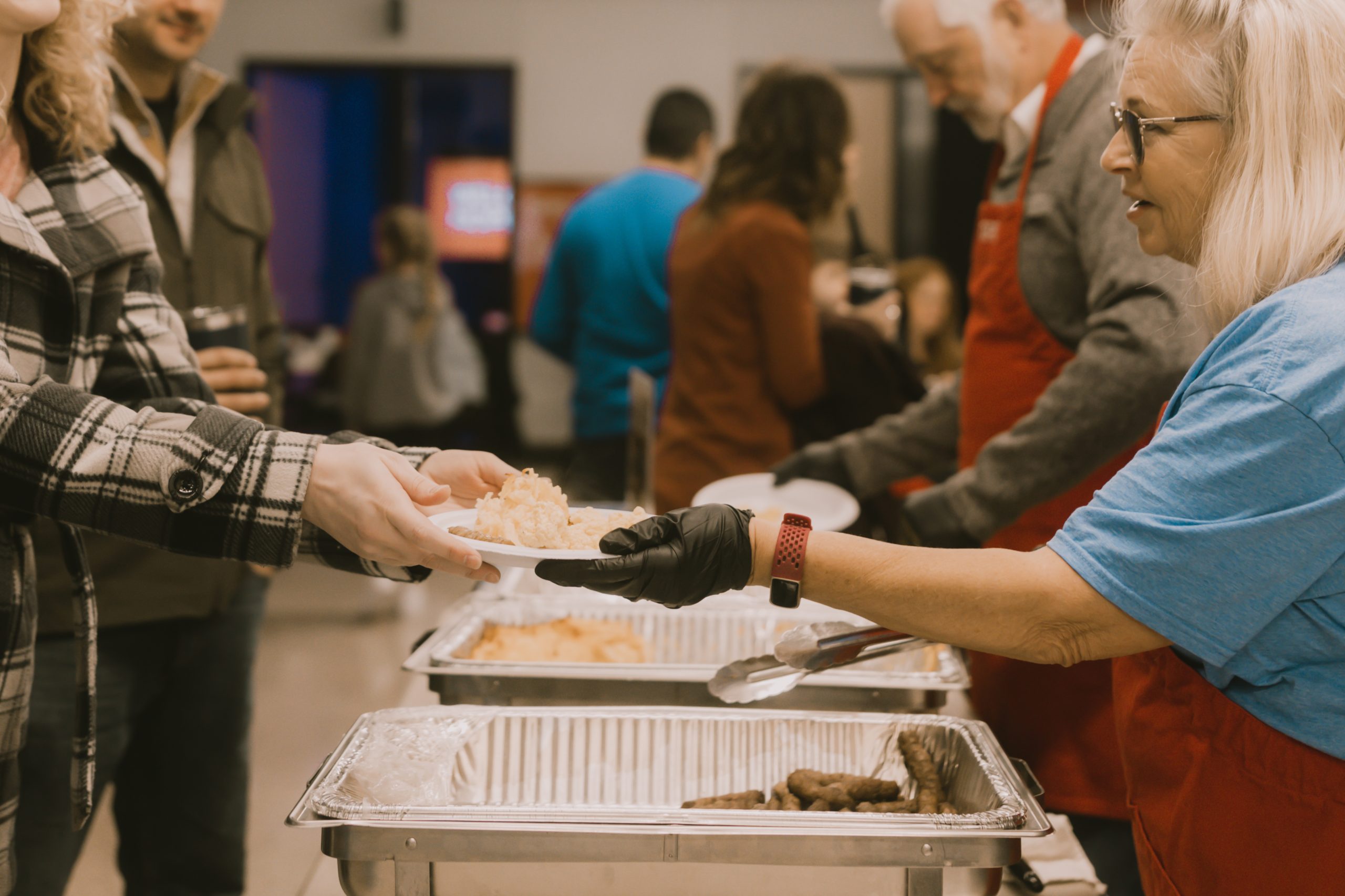 Volunteer serving breakfast to members after a church service.