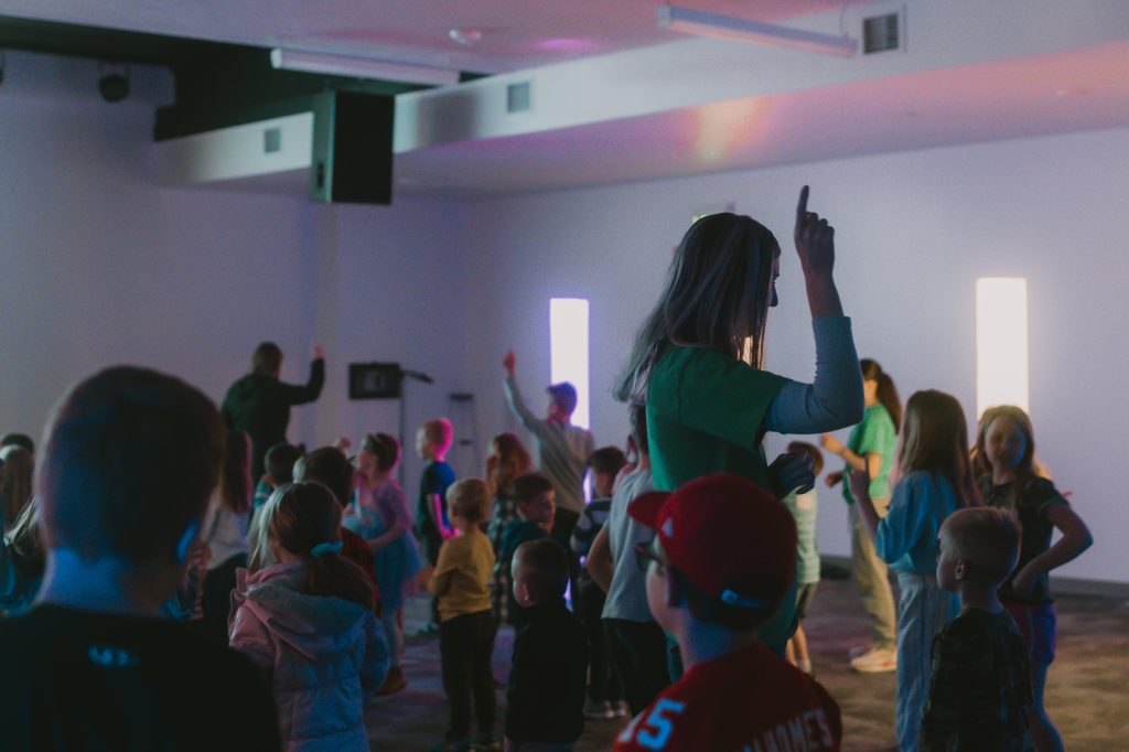 Volunteer dancing and leading children during a youth ministry event