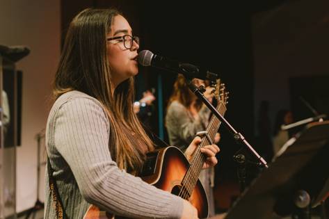 Woman singing and playing guitar on stage