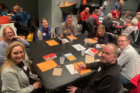 An Alpha group gathered at a table smiling at the camera