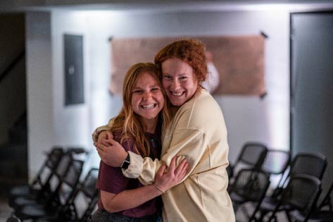 Women hugging in college classroom 