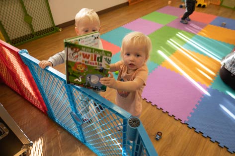 Two children in the nursery, one holding a book