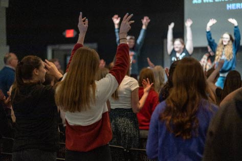 Group of PowerLife students singing and raising their hands