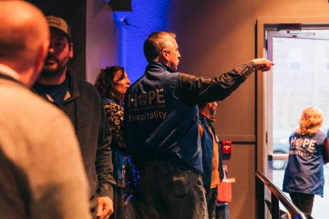 A man in a Hope volunteer vest pointing the way