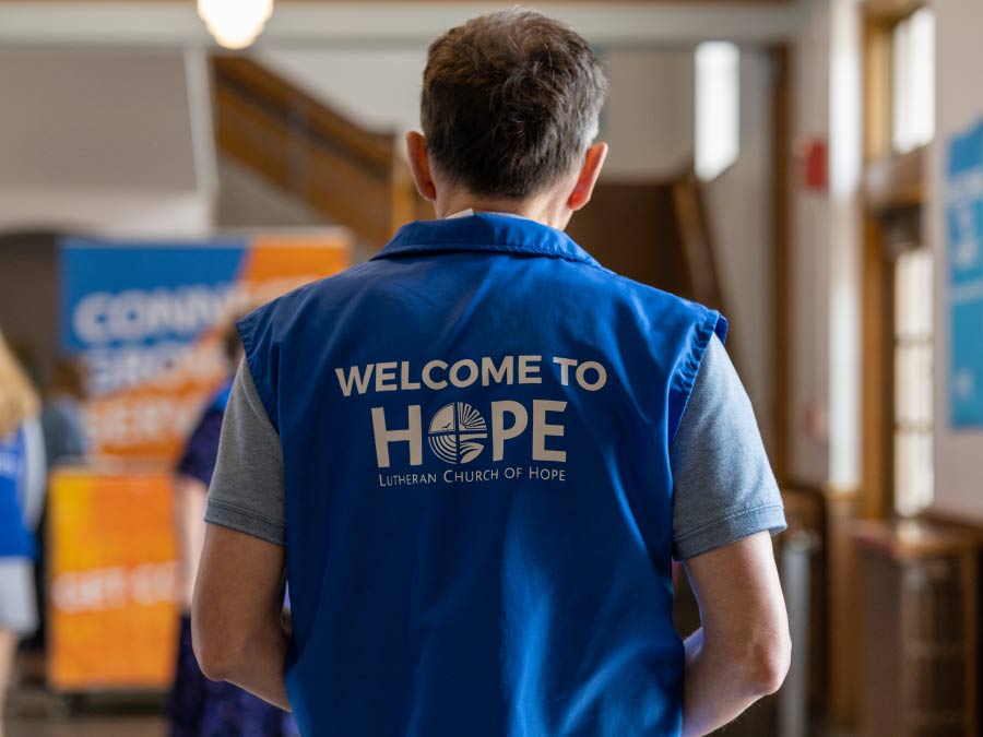 The back of a blue volunteer vest which reads Welcome to Hope